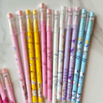 Colorful assortment of pastel Sanrio gel pens in soft pink, sunny yellow, lavender, sky blue, and white featuring Hello Kitty, Pompompurin, My Melody, Cinnamoroll, Kuromi, and Pochacco