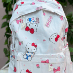 White canvas daypack featuring an all-over Hello Kitty print with red bows, strawberries, pink hearts, and a front zippered pocket