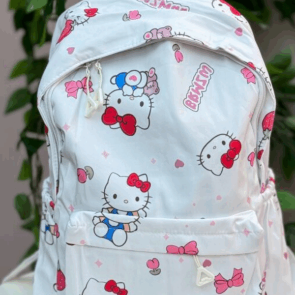 White canvas daypack featuring an all-over Hello Kitty print with red bows, strawberries, pink hearts, and a front zippered pocket