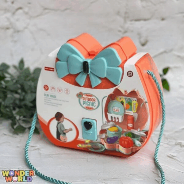 A structured hard-shell accessory case in warm coral pink with a large sculpted seafoam-blue bow clasp, styled with a twisted satin-sheen rope strap and showcasing illustrated picnic details