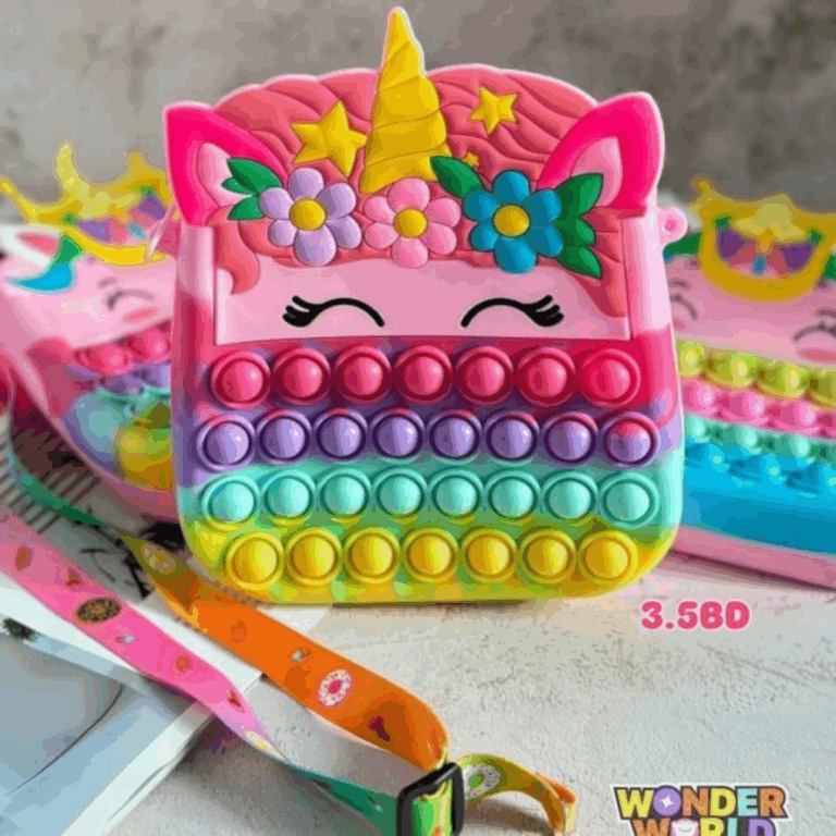 A unicorn-shaped silicone pop-it purse featuring a bright pink face with closed sleeping eyes, a sculpted yellow horn surrounded by stars, a cute three-flower crown in purple, pink, and blue, and a vibrant rainbow gradient body of pop-it bubbles, shown with a colorful patterned shoulder strap