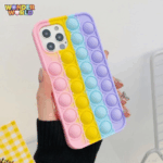 A close-up display of an oversized premium protective phone case held in a hand, showcasing expanded vertical stripes of soft silicone pop-it bubbles in a soothing gradient of pastel pink, sunlit yellow, mint blue, and lavender purple