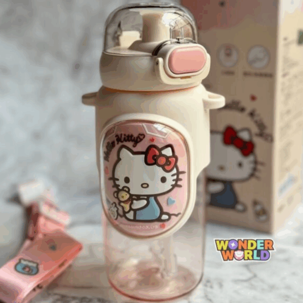 A clear drink bottle with a translucent pink bottom, a cream-colored top cap with a pastel pink pop-up locking button under a clear dome cover, wrapped in a cream silicone protective sleeve featuring a large oval plaque of Hello Kitty in her blue overalls holding a teddy bear, shown with its matching pink adjustable fabric shoulder strap