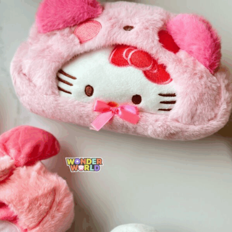 A close-up shot of a soft, fuzzy pastel pink plush pouch showing Hello Kitty's embroidered face framed by a cozy pink hood with prominent plush pink ears and a tiny pink satin bow under her chin
