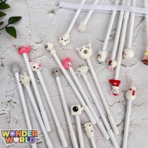 A lovely arrangement of cream-white gel pens, each decorated with a small, colorful sculpted character topper such as a tiny pink narwhal, a sleeping kitty, and a miniature holiday stocking