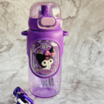 A close-up view of a translucent purple drink bottle with a matching deep purple silicone protective sleeve featuring a prominent oval plaque of Kuromi wearing a pink-and-white striped bow next to a coffee cup, complete with a translucent lavender locking dome lid, a light pink push-button, and a coordinating purple woven shoulder strap