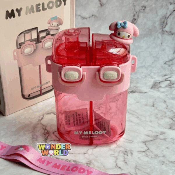 A dual-compartment translucent rose-pink water bottle wrapped in a pastel-pink silicone shoulder sleeve with two rounded cream push buttons, topped by dual translucent red lids with a tiny 3D My Melody figure wearing a blue bow resting on one side, shown with a matching pink character strap