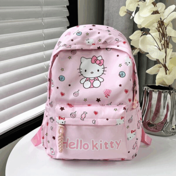 Detailed view of a light pink Hello Kitty daypack with candy and star patterns, a zippered front pocket, and side drink pockets on a table