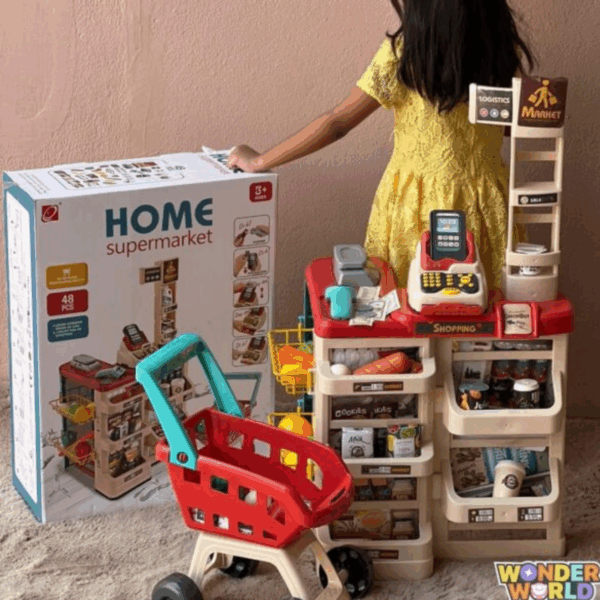 A multi-tiered toy supermarket checkout stand in cream and crimson red with shelves stocked with play goods, a toy register, and a small red shopping cart with a turquoise handle