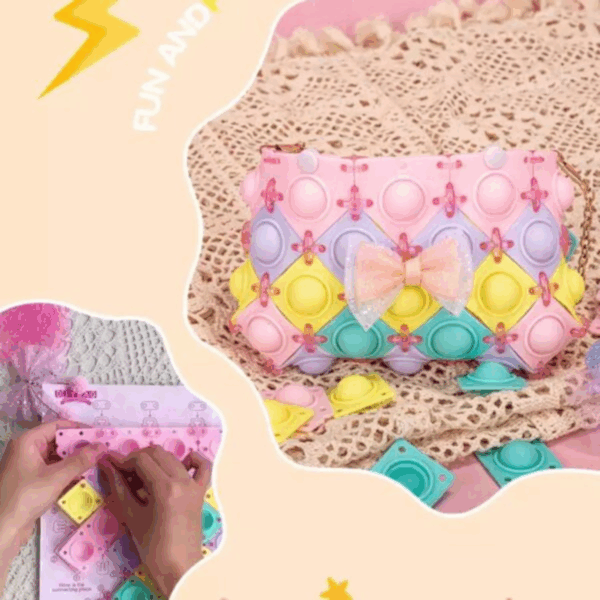 A close-up display of a DIY pastel-colored pop-it purse constructed from interlocking diamond panels of pink, lavender, yellow, and mint green, connected with tiny clear-pink joints, featuring a shimmering glitter-tulle pink bow at the center and resting on a textured cream crochet surface next to separate loose pop-it puzzle tiles