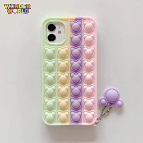 A close-up display of a whimsical silicone phone case featuring vertical stripes of soft pop-it bubbles in a soothing gradient of mint green, sunlit yellow, pastel lavender, and blossom pink, sculpted into miniature mouse head silhouettes, complete with a matching lavender mouse-ear pop-it charm attached by a silver ball chain