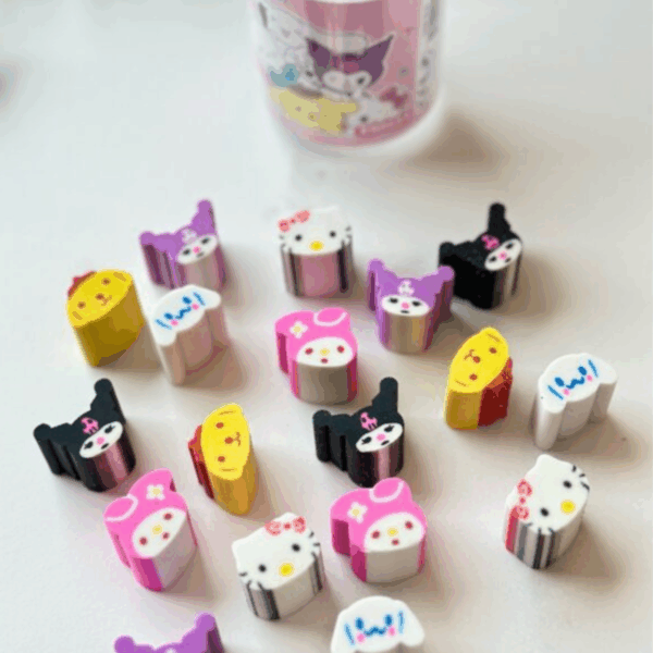 A scattering of colorful, miniature die-cut rubber erasers shaped like Sanrio character heads, showcasing Hello Kitty, Cinnamoroll, My Melody, Pompompurin, and Kuromi in both purple and black hoods, set against a clean white surface with a soft-focus clear plastic tub in the background