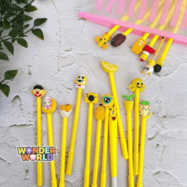 A flat-lay view of several bright sunshine-yellow gel pens spilling out of a frosted, pink-striped slide-zip pouch on a rustic white textured surface with soft green leaves in the corner, each pen crowned with a unique, colorful 3D silicone topper including a fresh yellow lemon wedge, a winking kitty on a golden crescent moon, a yellow camera, a hatching egg yolk, and a cute puppy with a red bow tie