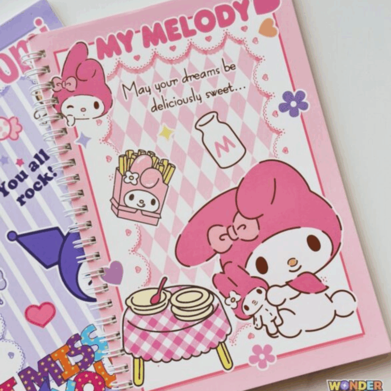 A pink spiral notebook featuring a center panel with a pink and white argyle diamond pattern. It shows My Melody sitting with her small plush toy next to a gingham-clothed table, accompanied by illustrations of a milk bottle, French fries, and the inspirational quote, "May your dreams be deliciously sweet...