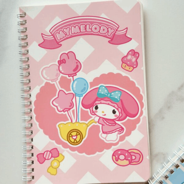 A pink and white diagonal gingham spiral notebook featuring My Melody pushing a yellow cart filled with star-shaped and bunny-shaped balloons, set against a large scalloped pink heart background with a "My Melody" banner at the top
